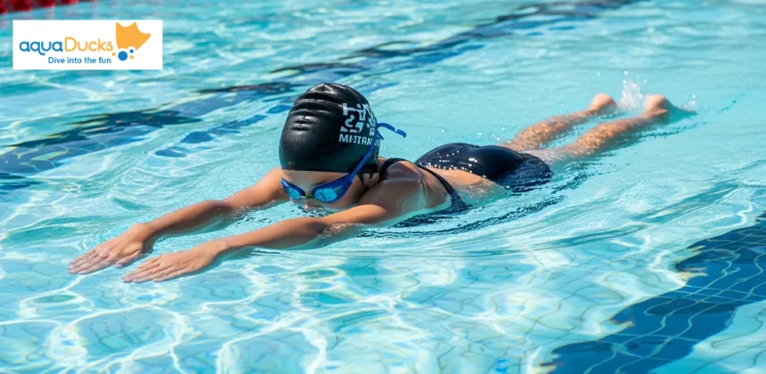 Child demonstrating correct freestyle swimming body position in pool