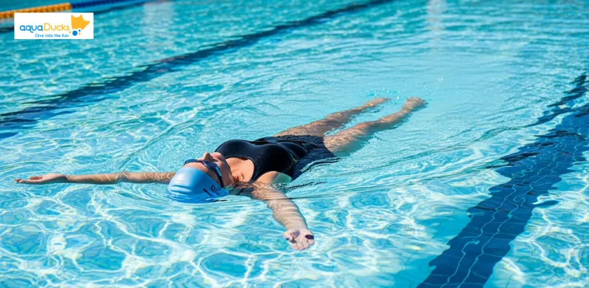 Swimmer performing elementary backstroke while floating on their back in a calm swimming pool.