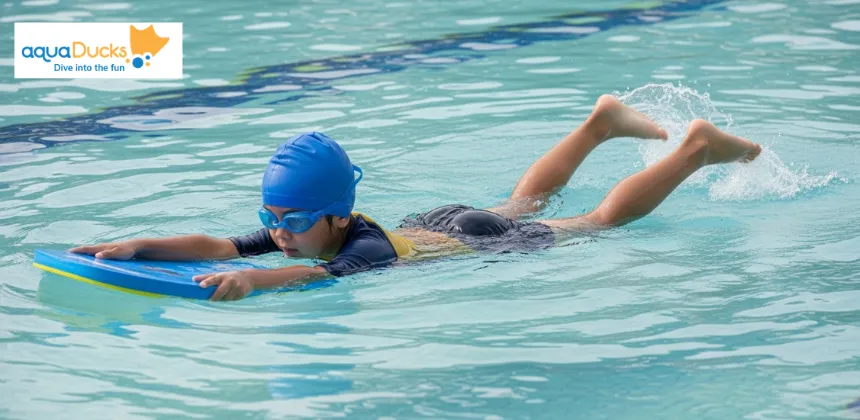 A young student uses a kickboard to practice the flutter kick, a basic kicking technique for movement, during swimming lessons for beginners.