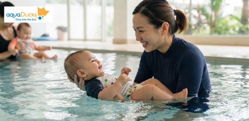 A parent holds their baby in the water during an interactive swimming lesson, noting that goggles and floats are not required.