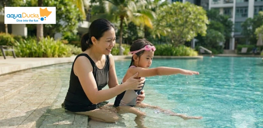 A parent helping a child practice proper arm reaching and pulling movements on the pool steps to build coordination for swimming.