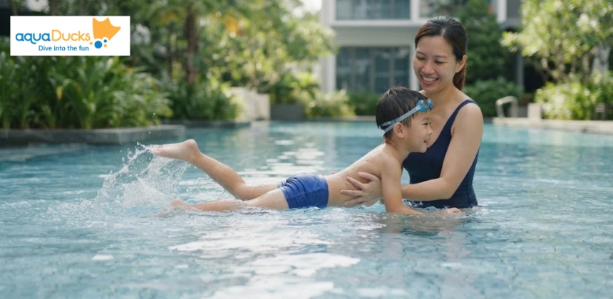 A parent supporting their child as they practice kicking legs in the pool to learn basic swimming movement and improve their technique.