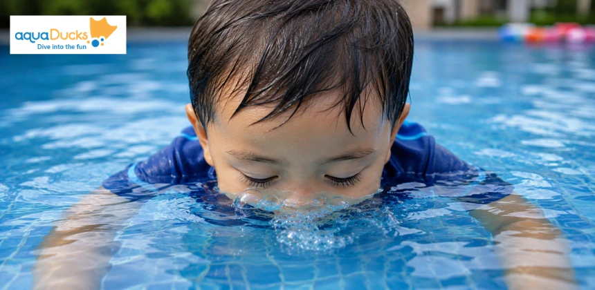 Toddler enjoying swimming games for toddlers by blowing bubbles, practicing fun games to play in swimming pool safely.