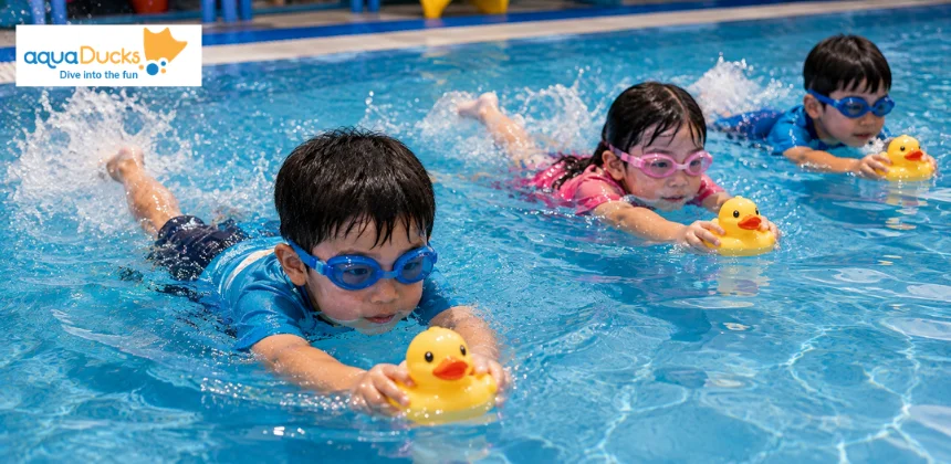 Children participating in swimming race games with rubber ducks, enjoying active swimming games for kids in the indoor pool.