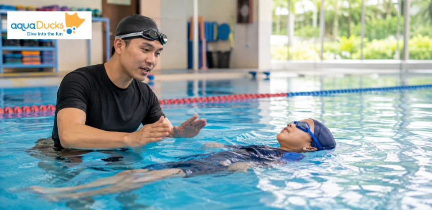 Instructor teaching a child to float in a pool, demonstrating real swimming lessons as part of crucial swimming safety.