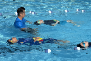 A pool instructor and three children enjoy swimming lessons together in a pool aquaDucks