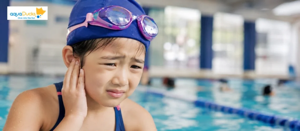 Can You Swim With an Ear Infection? Young swimmer holding her ear in pain by the pool edge during swim lessons