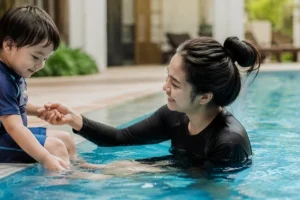 A mother helping her son at the pool to help your child overcome their fear of water and feel safe in the water.