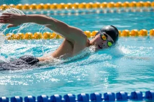 Young athlete practising freestyle stroke in a training pool, refining arm movement, breathing, and posture while learning proper swimming strokes.