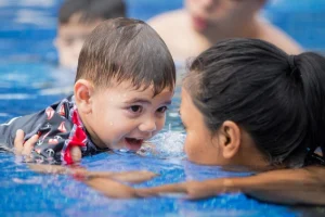 An instructor practicing active supervision with a toddler in a swimming pool to demonstrate essential water safety for kids.